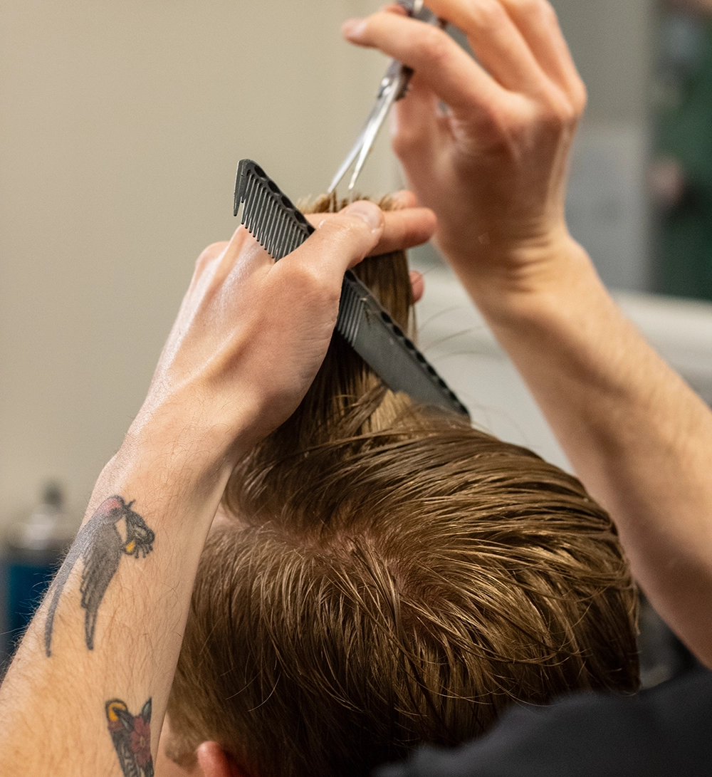 A closeup of a customer receiving a haircut at the Quaker Village Barber & Style Shop in Greensboro, NC.